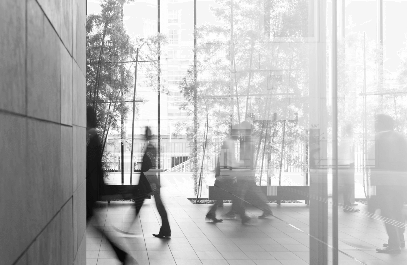 A wide view into the foyer of an office building where blurs of people walk through