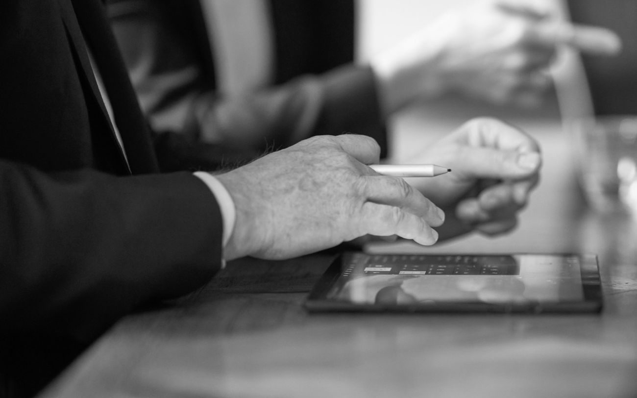 in black and white, a lawyer's hands organise tasks on an ipad sitting on a desk table